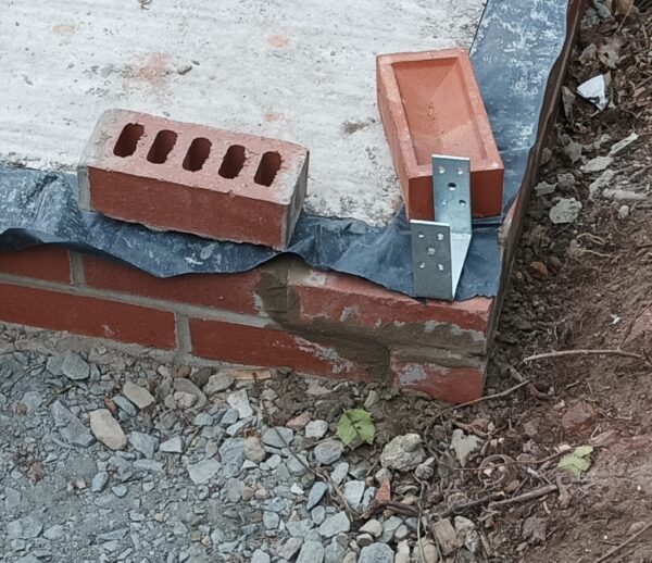 The corner of some brick work with the metal fitting in place. An engeering brick and London stock brick are also shown.