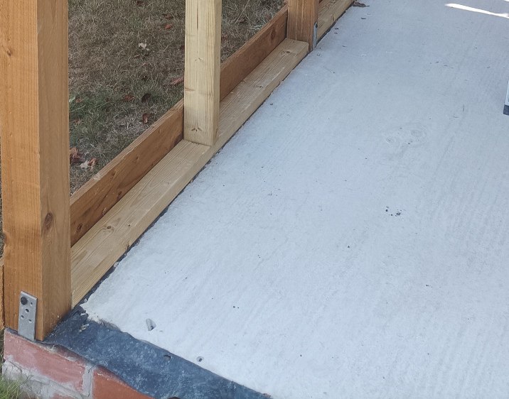 A concrete base with wooden posts and timber with gravel boards attached